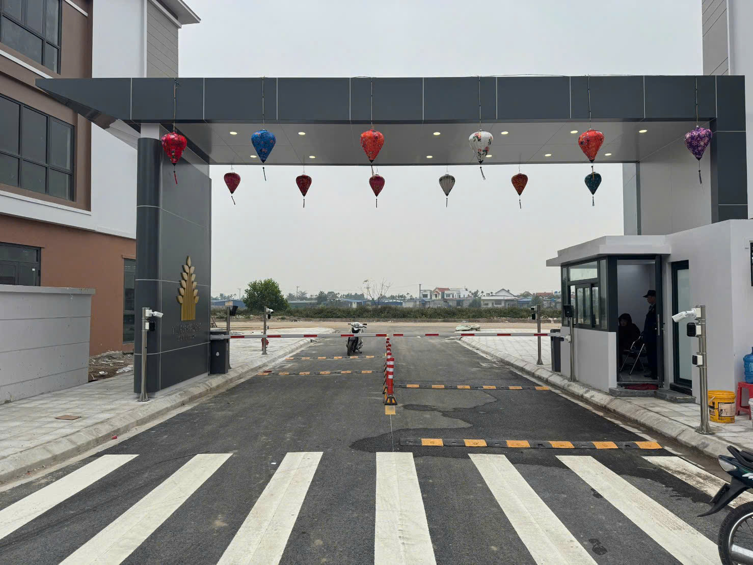 Cổng ra vào khu đô thị với chòi bảo vệ, barie tự động và đèn lồng trang trí nhiều màu sắc